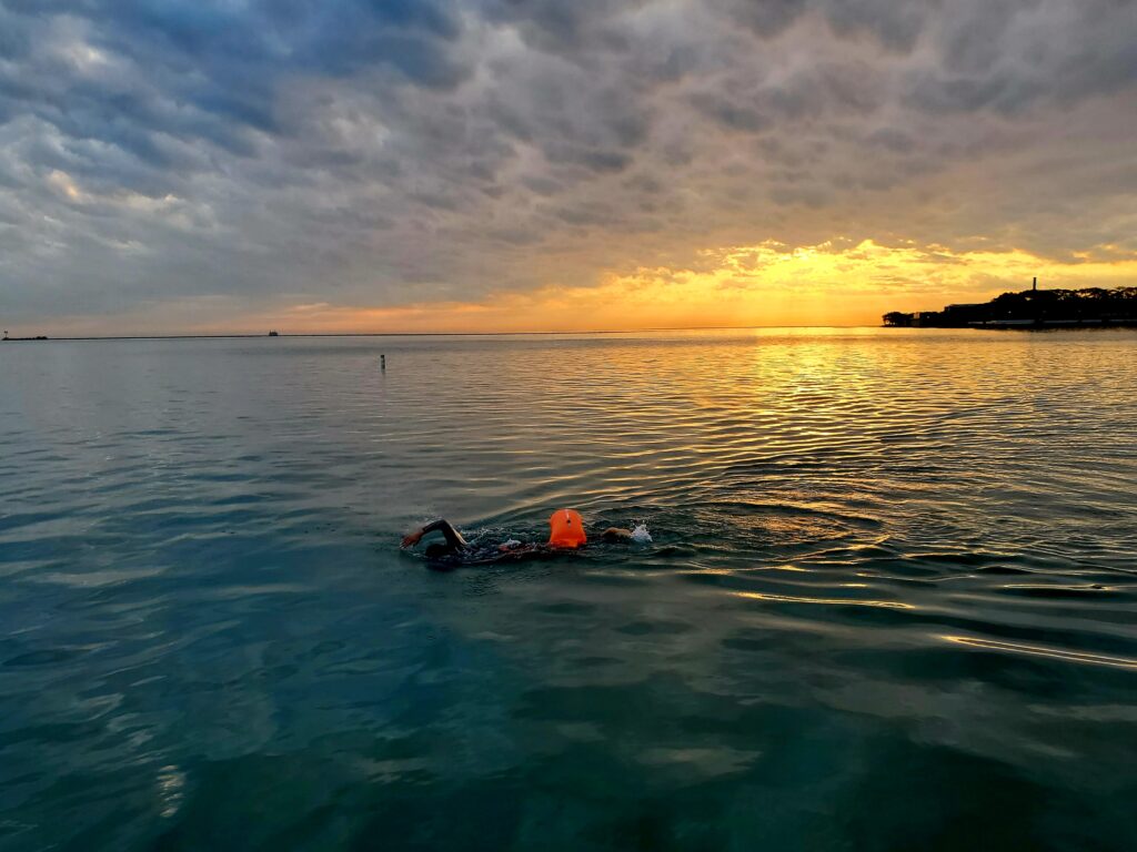 Sunrise and clouds behind an open water swimmer at Ohio Street Beach