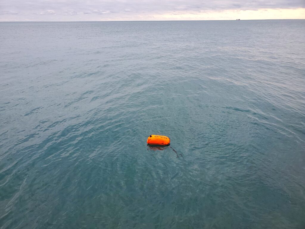 bright orange swim buoy is the only thing visible in the foreground