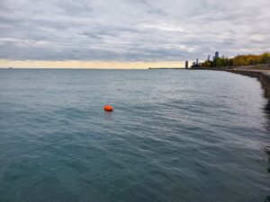 A high visibility orange swim buoy tow float improves visibility to other swimmers and watercraft during an open water swim.