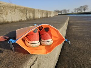 Large running shoes fit in the dry bag of the New Wave Open Water Swim Buoy